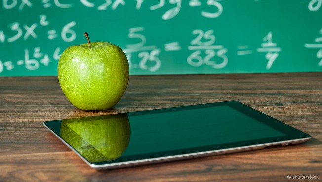 Tablet mit Apfel vor Kreidetafel