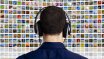 Medien-Motiv: Mann mit Kopfhörern von einer Wand mit zahllosen Bildschirmen